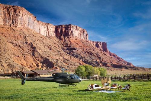 a helicopter parked in a field in front of a mountain at Red Cliffs Lodge Moab in Moab