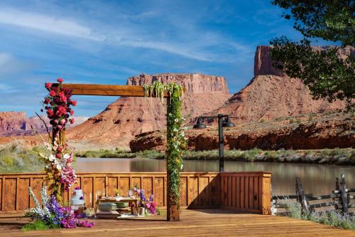 an arch with flowers on a wooden deck next to a river at Red Cliffs Lodge Moab in Moab