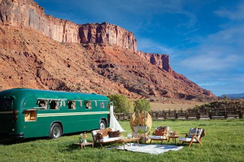 a green bus parked in a field near a mountain at Red Cliffs Lodge Moab in Moab