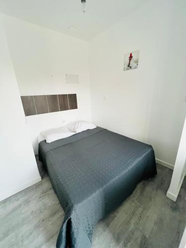 une chambre avec un lit dans une pièce blanche dans l'établissement Hotel Le Breton, à Indret