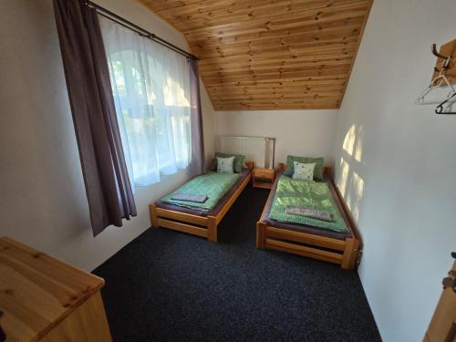 two beds in a room with a window at Penzion pod Špičákem in Tanvald