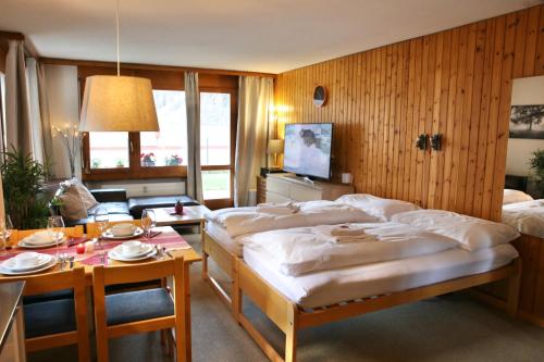 a bedroom with two beds and a table with plates on it at Monte Rosa Apartments Täsch in Täsch