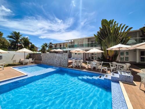 a swimming pool with chairs and umbrellas next to a building at Hotel Vivenda dos Corais in Porto De Galinhas