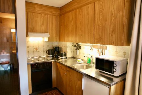 a small kitchen with a microwave and a sink at Monte Rosa Apartments Täsch in Täsch