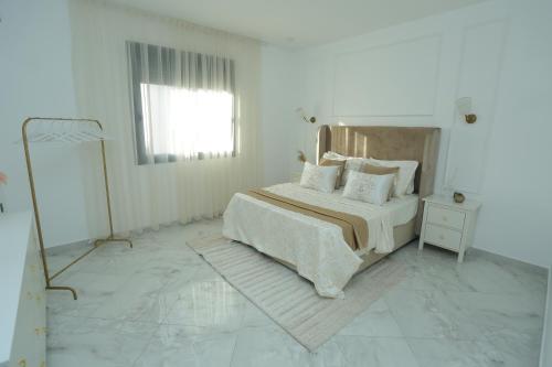 a white bedroom with a bed and a mirror at Luxueux T3 à Oran. in Oran