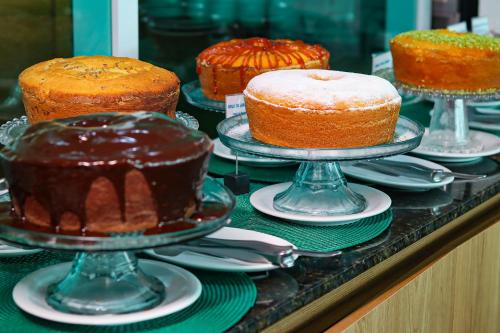 a display of cakes on plates on a table at Hotel Vivenda dos Corais in Porto De Galinhas