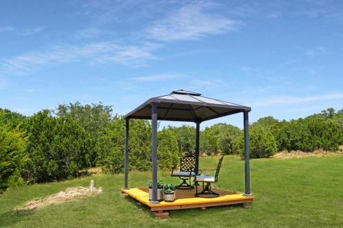 a gazebo with a bench and a chair in a field at Arbor House of Dripping Springs - Garden House in Dripping Springs