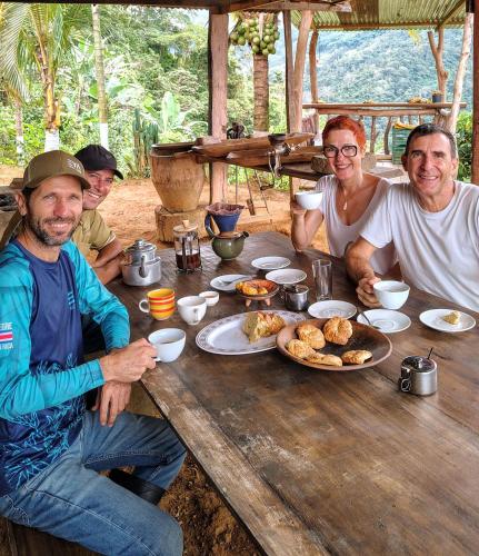 a group of people sitting around a wooden table with food at EYA Ecolodge in San Isidro