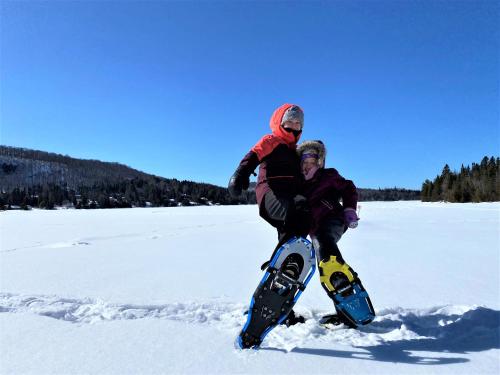 a couple of people standing in the snow with snowboards at Le1617 - Quai privé, Lac-Les chalets dans le nord in Sainte-Lucie-de-Doncaster