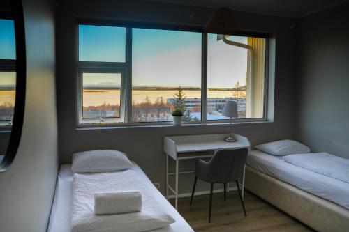 a room with two beds and a desk and windows at Hótel Laugarvatn in Laugarvatn
