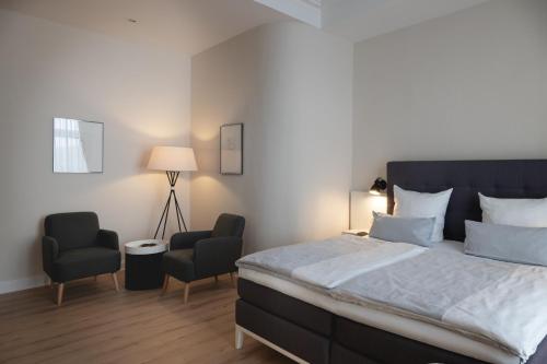 a bedroom with a large bed and two chairs at Rheinhotel Dreesen in Bonn