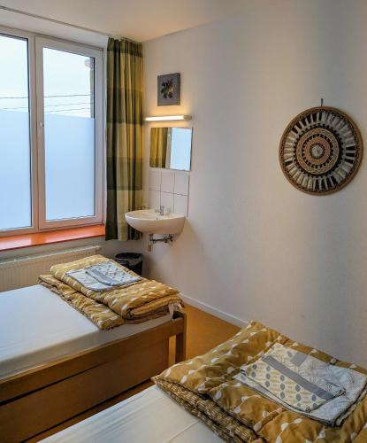 two beds in a room with a sink and a window at Le Fagotin - Youth hostel in Stoumont