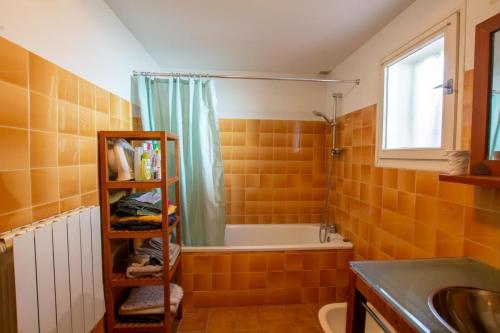 an orange tiled bathroom with a shower and a sink at La maison de famille in Mussidan