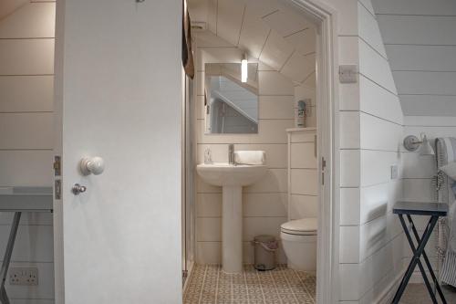 ein Badezimmer mit Waschbecken, Toilette und Spiegel in der Unterkunft Bantham House, Bantham, South Devon - a few steps from golden sandy beaches in Bantham