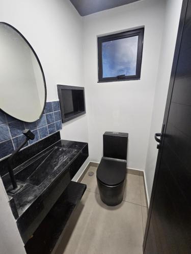 a bathroom with a sink and a toilet and a mirror at Lofts 4 Elementos - Água - Martim de Sá - Caraguatatuba in Caraguatatuba
