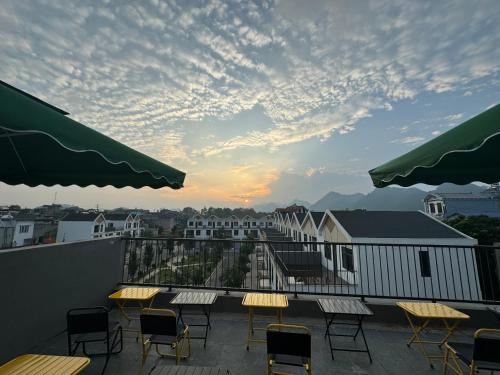 a balcony with tables and chairs and a sunset at Liverpool House Mộc Châu in Mộc Châu