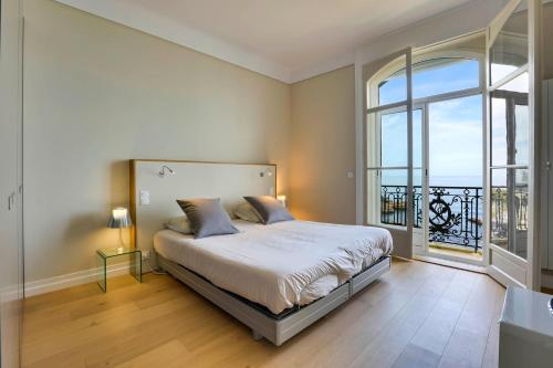 une chambre avec un lit et une grande fenêtre dans l'établissement REINE - Vue imprenable Grande Plage, à Biarritz