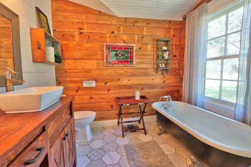 a bathroom with wooden walls and a tub and a sink at Serendipity Farmhouse in Wimberley