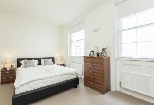 a white bedroom with a bed and two windows at Covent Garden 2BR - Urban Chic Apartment in London