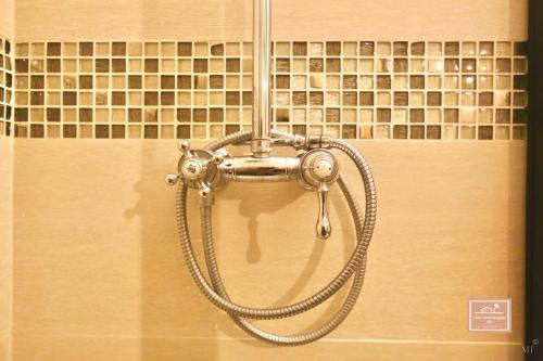 une pomme de douche dans une salle de bain avec un mur carrelé dans l'établissement Le Kanumera, piscine et clim, à La Seyne-sur-Mer