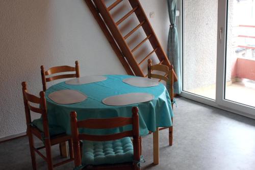 une table et des chaises avec une table bleue et un escalier dans l'établissement Studio Ax Pyrénées, à Ax-les-Thermes