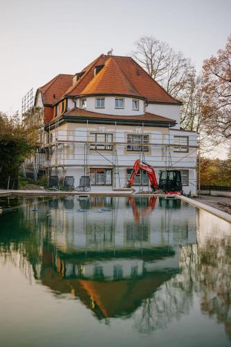 a large white building with a reflection in the water at Villa am Park in Bad Tölz