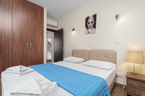 a bedroom with a large bed with a blue blanket at Seafront Protaras Villas in Protaras