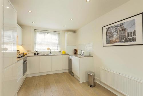 a kitchen with white cabinets and a sink at Covent Garden 2BR - Urban Chic Apartment in London