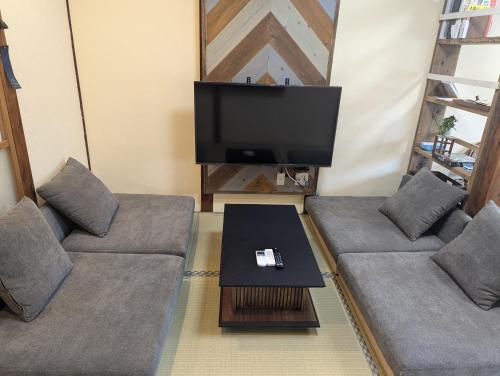 a living room with two couches and a tv at 一棟貸し宿 ローカルプライド大和高田 in Yamatotakada