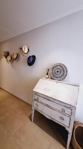 - une commode blanche dans une pièce avec des chapeaux au mur dans l'établissement Superbe appartement terrasse piscine vue panoramique mer et montagnes, à Mandelieu-la-Napoule