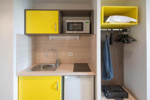 a small kitchen with a sink and a microwave at Westlodge Dardilly Lyon Nord in Dardilly