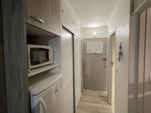 une petite cuisine avec un four micro-ondes et un couloir dans l'établissement Studio rénové 3*, balcon sud, pied pistes – Wifi, lave-linge, lits superposés, proche commerces - FR-1-787-53, à Laveissière