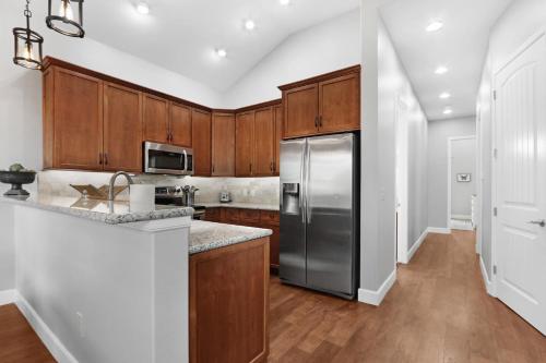 a kitchen with wooden cabinets and a stainless steel refrigerator at Comal Cottage in Canyon Lake