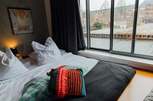 a bed with a pillow on it in front of a window at ClinkMama in Amsterdam