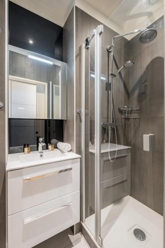 La salle de bains est pourvue d'une douche et d'un lavabo blanc. dans l'établissement Veeve - Peaceful Gallery, à Paris