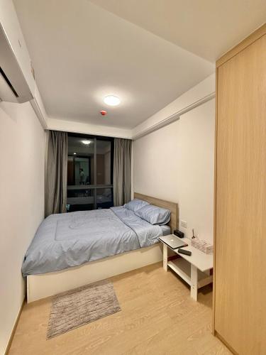 a small bedroom with a bed and a table at Regal 40 Srinakarin Apartment in Bangkok