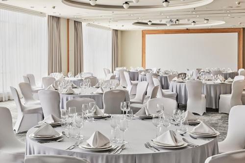 a conference room with tables and chairs and a screen at Sheraton Poznan Hotel in Poznań