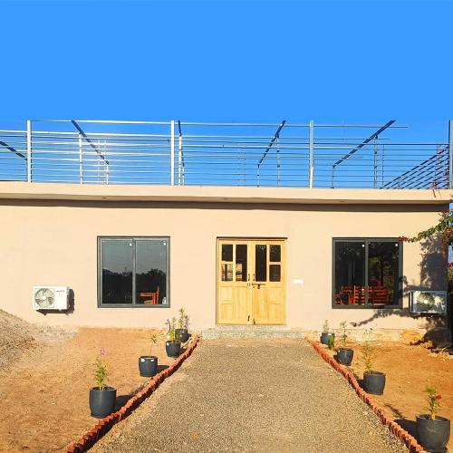 a house with a door and potted plants in front of it at Thour Nature Resort - Jawai Leopard Safari Camp in Bera