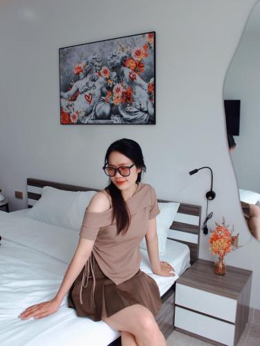 a woman is sitting on a bed at Liverpool House Mộc Châu in Mộc Châu