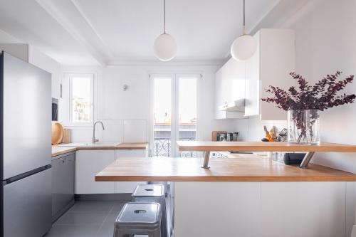 une cuisine avec des armoires blanches et un comptoir en bois dans l'établissement Veeve - Cotton White, à Paris