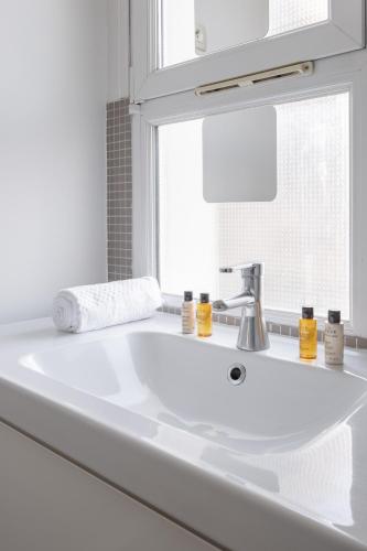 La salle de bains est pourvue d'un lavabo blanc et d'une fenêtre. dans l'établissement Veeve - Cotton White, à Paris