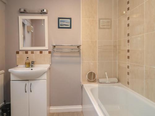 a bathroom with a bath tub and a sink and a mirror at Charleston Cottage in Bridport