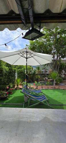 two lawn chairs and an umbrella in a yard at บ้านพักแม่หมูเกาะล้าน in Ko Larn