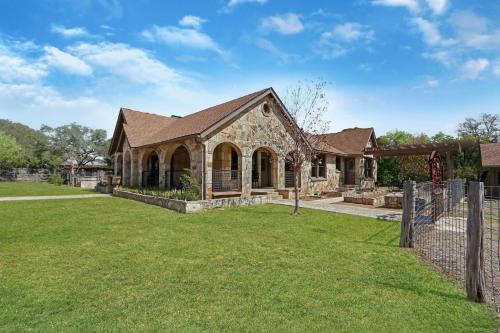 a stone house with a fence and a yard at Milk Bath Springs House in Dripping Springs