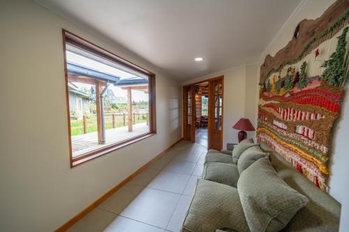 a living room with a couch and a window at Parque la Pajarera in Puerto Varas