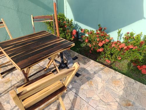 a wooden table and chairs next to some flowers at Casa lagoa dos tambaquis in Estância