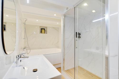 une salle de bain blanche avec une douche et un lavabo dans l'établissement Appartement duplex in Saint-Germain-des-Prés, à Paris