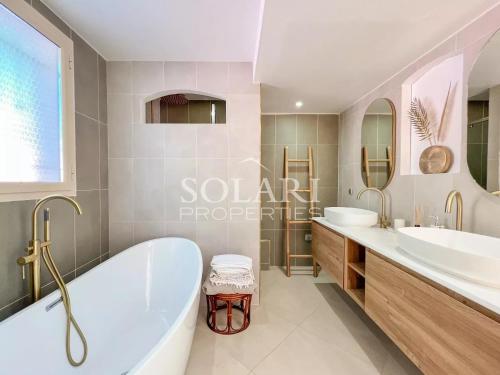 La salle de bains est pourvue de 2 lavabos, d'une baignoire et de miroirs. dans l'établissement Villa Esterella, à Mandelieu-la-Napoule