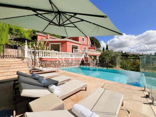 Cette villa dispose d'une piscine avec des chaises et un parasol. dans l'établissement Villa Esterella, à Mandelieu-la-Napoule