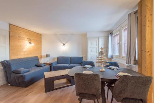un salon avec un canapé bleu et une table dans l'établissement Appartement Cimes Étoilées - Welkeys, à Megève
